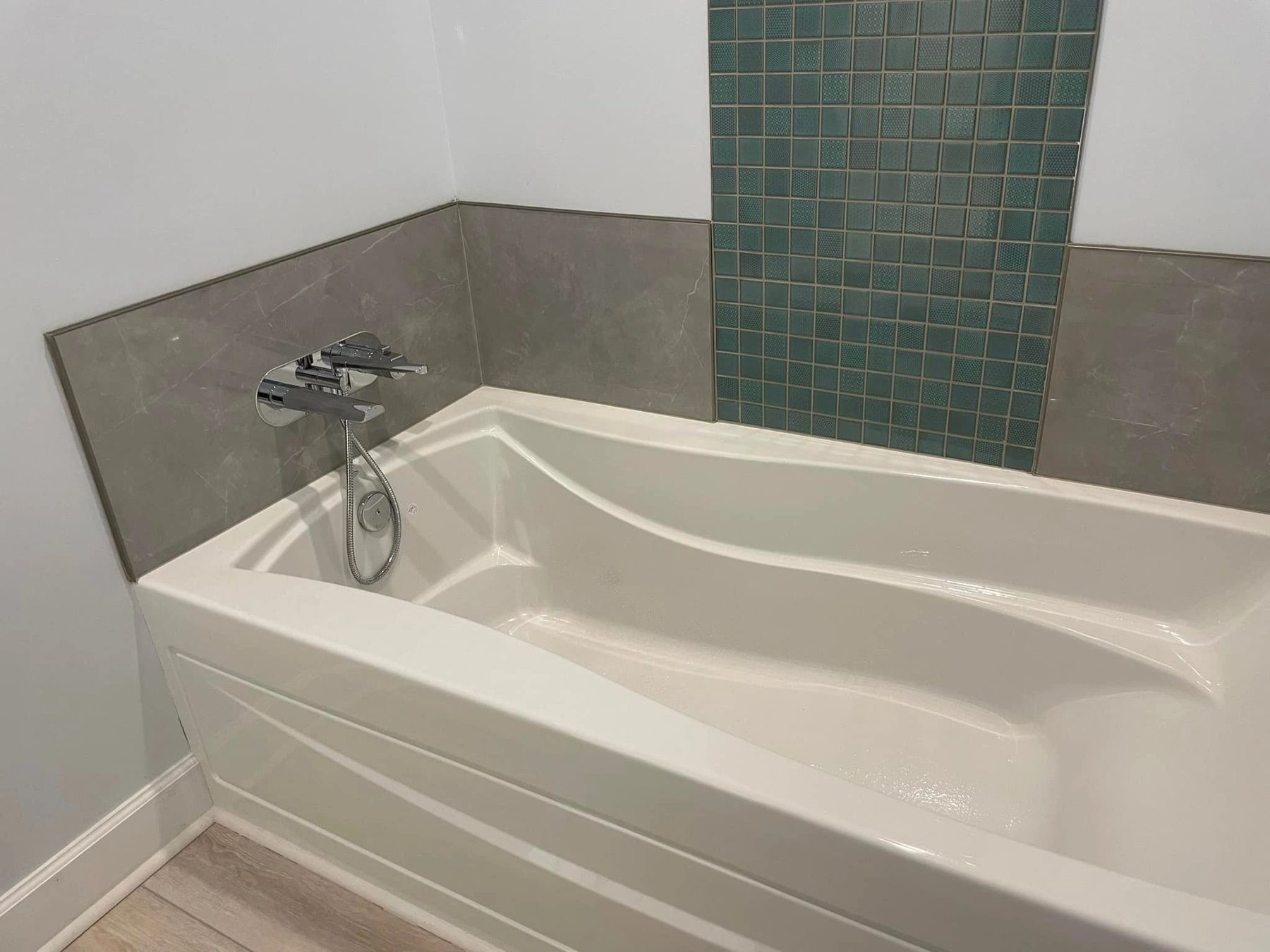 Bath with teal mosaic accent tile above the tub