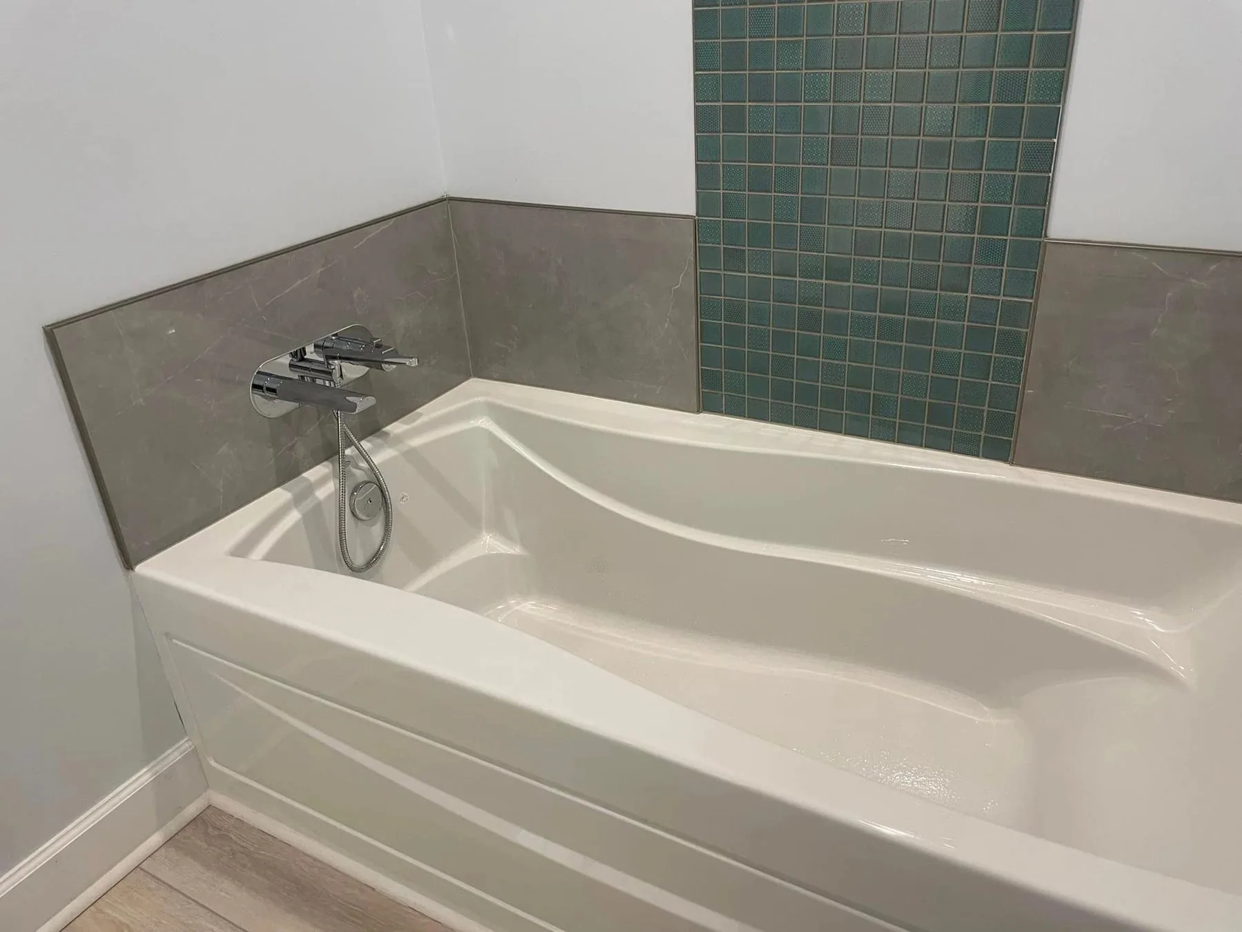 Bath with teal mosaic accent tile above the tub