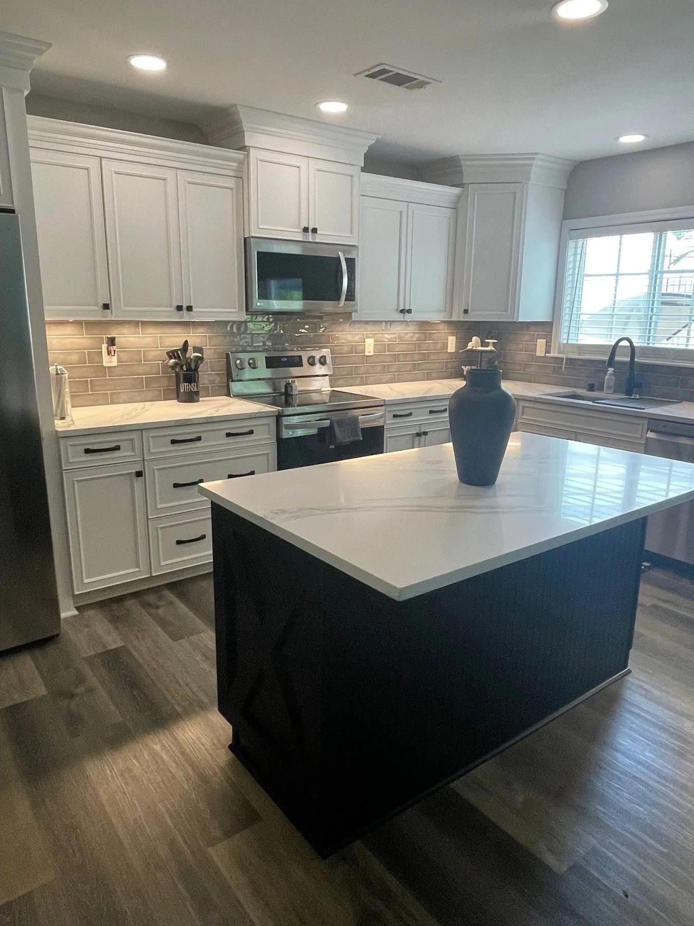 Kitchen with black island and white cabinets by Queen City Kitchen and Bath