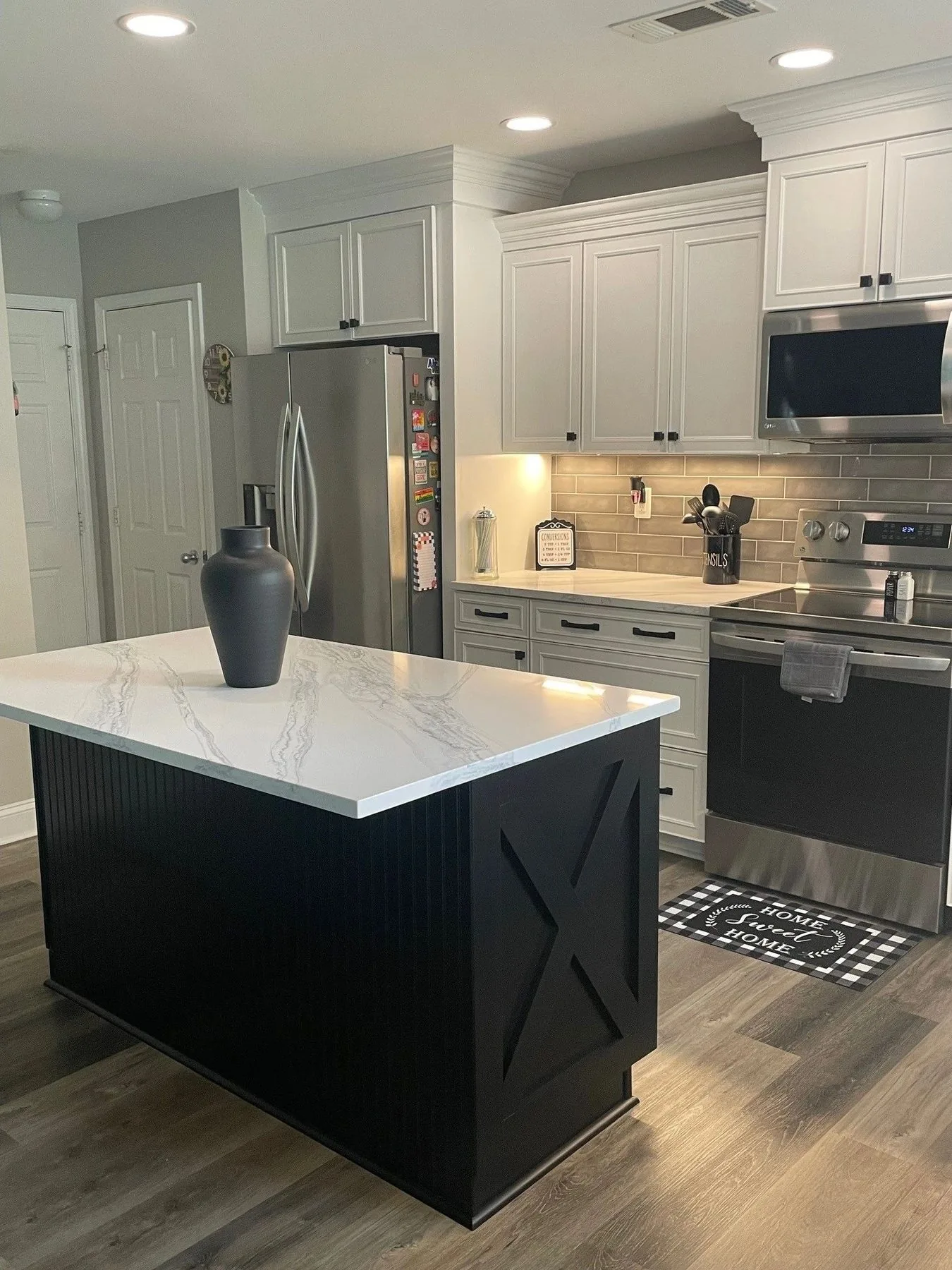 Kitchen with black island, white perimeter cabinets, and quartz countertop