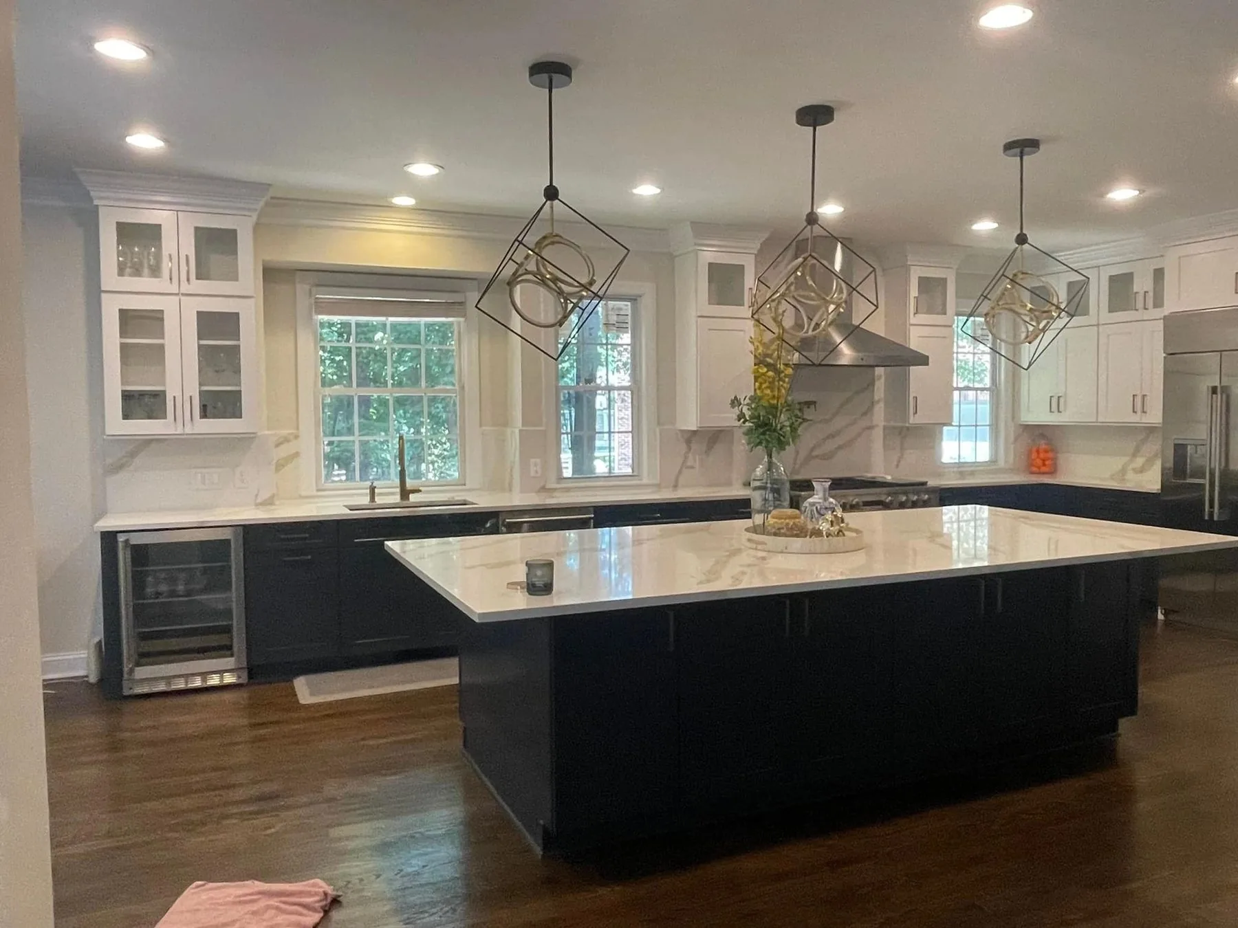 Remodeled kitchen with navy island, white cabinets, and marble backsplash